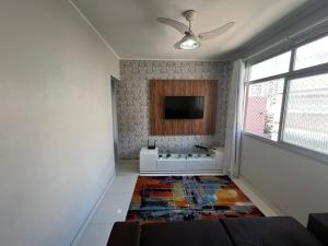 a living room with a couch and a tv on the wall at Itapuã - 4 Minutos da Praia - Apartamento Espaçoso - 3 Quartos in Vila Velha