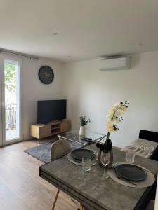 a living room with a table and a tv at Longchamps 3 - Modern cocoon Close to Marlioz thermal baths in Aix-les-Bains
