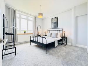 a white bedroom with a bed and a window at Skyline View Apartment in Edinburgh