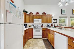 a kitchen with white appliances and wooden cabinets at Spring Lake Retreat in Rockaway Beach +14 photos