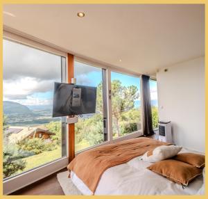 una camera da letto con un letto grande con una grande finestra di Villa vue Lac Léman et montagne Proche Genève a Cranves-Sales