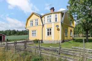 a yellow house in a field next to a fence at JON440-Paulistrom-Haesslehult-6 in Hässlehult