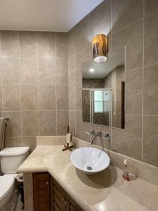 a bathroom with a sink and a toilet and a mirror at Real Marina Blue 102B - Santa Cruz in Santa Cruz Huatulco