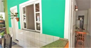 a kitchen with a green and white wall and a window at Mares e Flores de Bombinhas in Bombinhas