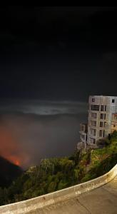 a building on the side of a mountain at night at السفير in Fayfāʼ