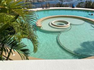 a swimming pool with a spiral in the water at Oceanview Punta Arrocito Luxury Condo, Near Arrocito Beach in Santa Maria Huatulco