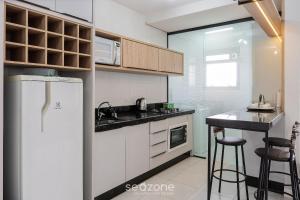 a kitchen with a white refrigerator and a counter at Apto com varanda e churrasq 500m da praia RML605 in Imbituba