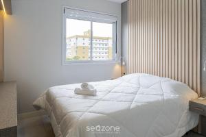 a white bed in a room with a window at Apto com varanda e churrasq 500m da praia RML605 in Imbituba