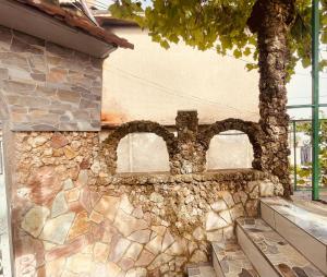 pared de piedra con 2 ventanas en un edificio en Nafo Rooms, en Gjirokastra