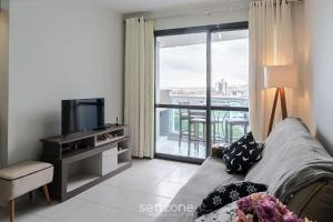 a living room with a couch and a television at Apto com varanda e churrasq 500m da praia RML605 in Imbituba