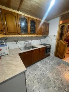 Una cocina con gabinetes de madera y un fregadero. en Nafo Rooms, en Gjirokastra