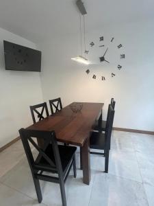 a dining room table with chairs and a clock on the wall at Apartament pod ŚWIERKIEM in Krupski Młyn