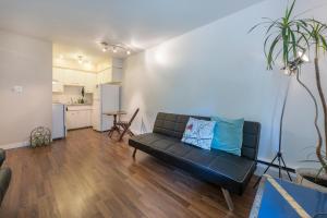 a living room with a black couch and a kitchen at One Bedroom Suite in perfect location Vancouvers Mount Pleasant in Vancouver