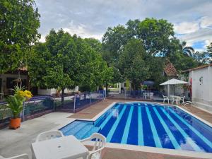 a large swimming pool with chairs and tables and trees at Hotel Refugio Bike in Mariquita