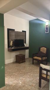 a living room with a tv and a chair at Casa Serra da Canastra - Chicó in São Roque de Minas