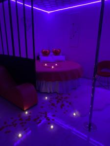 a purple room with a bed with petals on the floor at Aphrodite LoveRoom in Château-Landon