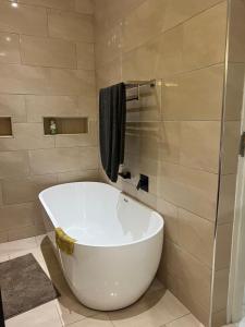 ブランタイヤにあるThe Cozy Nookのバスルーム(白いバスタブ、シャワー付)