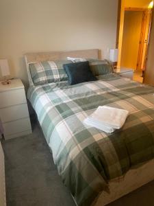a bedroom with a large bed with a plaid blanket at 33 Liberator Drive, Kirkwall in Orkney