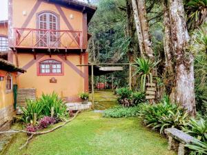 a house with a tree in front of a yard at Hospedaria Alecrim - Pousada Sustentável APA in Petrópolis