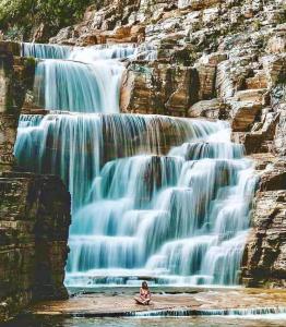 カピトーリオにあるHotel Restaurante e Camping Beija Florの滝前に座る者