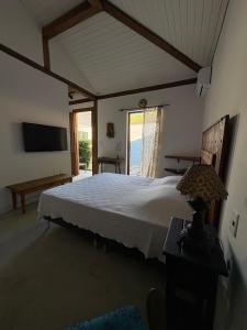 a bedroom with a large bed and a television at Gizele Sander Arte & Hospedagem in Ilhabela