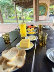 a table topped with plates of food and glasses of orange juice at Rancho Pouso da Gaivota in Muçuroca