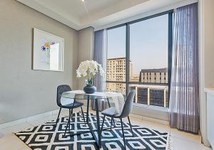 Un comedor con mesa y sillas y una gran ventana. en Sandton Skye Apartment, en Johannesburgo