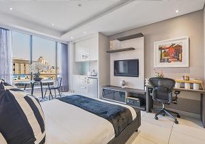 Un dormitorio con una cama y un escritorio con una computadora. en Sandton Skye Apartment, en Johannesburgo