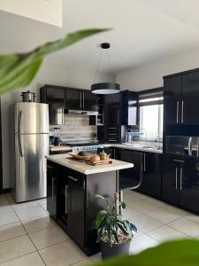 a kitchen with black cabinets and a stainless steel refrigerator at Residence in Chihuahua in Chihuahua