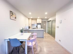 a kitchen and dining room with a white table and chairs at SUPER Location - Modern 2Br Apt-Pool & Gym V183 in Auckland