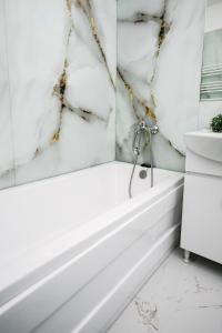 baño con bañera blanca y paredes de mármol en Escape Hub Residence Militari 2, en Chiajna 10 fotos más