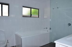 a white bathroom with a tub and a toilet at Double Island Dream - Rainbow Beach in Rainbow Beach +25 photos