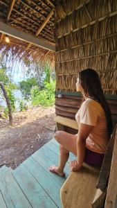 a woman sitting on a porch of a hut at Casa da Ilha Cotijuba in Belém +8 photos