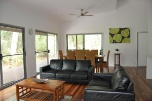 a living room with a black leather couch and a table at Csalt - Rainbow Shores in Rainbow Beach