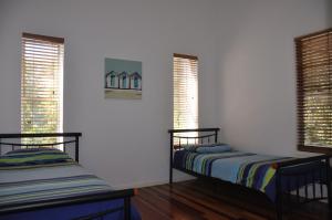 two beds in a room with two windows at Csalt - Rainbow Shores in Rainbow Beach