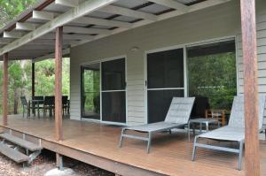 a screened in porch with chairs and a table at Csalt - Rainbow Shores in Rainbow Beach