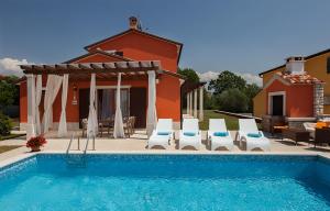 einen Pool mit Stühlen und ein Haus in der Unterkunft Villas Vilanija in Umag