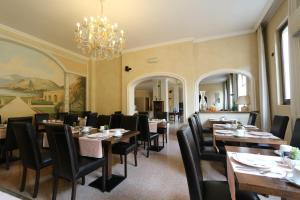 une salle à manger avec des tables et des chaises ainsi qu'un lustre dans l'établissement Hotel Dei Tigli, à Angera