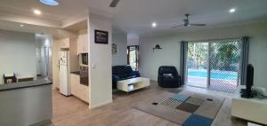 a living room with a couch and a kitchen with a pool at Shelleys - Rainbow Shores in Rainbow Beach