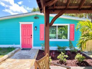 una casa blu con porte rosse e una panchina di Flamingo Cottage 2 bedroom a Jensen Beach