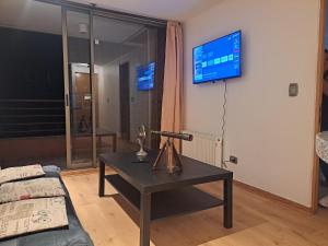 a living room with a table with a lamp and a tv at Apart Manquehue in Santiago