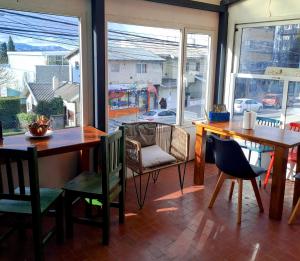 a dining room with two tables and chairs and windows at Nina Hostel in San Carlos de Bariloche