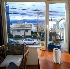 a table and chair in front of a large window at Nina Hostel in San Carlos de Bariloche