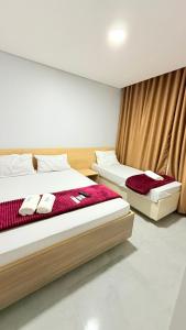 Dos camas en una habitación de hotel con sábanas rojas. en Hotel Vision Guaianases, en São Paulo