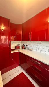 una cocina roja con encimeras blancas y armarios rojos en Cozy Apartment, en Londres