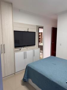 Un dormitorio con un televisor de pantalla plana y una cama. en Apartamento praia da Ribeira 2 quartos, en Angra dos Reis