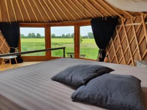 a bed with two pillows in a room with windows at Glamour-Camping in Hanshagen +11 photos
