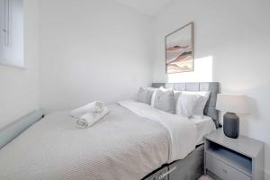 a white bedroom with a bed with white sheets and pillows at Luxurious 2 Bedroom Apartment in Coulsdon