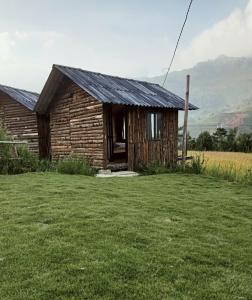 an old log cabin with a grass yard at Mẩy Lơ Homestay in Sa Pa