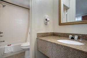 a bathroom with a sink and a toilet and a mirror at SureStay by Best Western Gonzales in Gonzales +7 photos